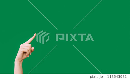 Pointing finger. Advertising background. Sale discount. Female hand showing recommending something invisible isolated on green empty space. 118643981