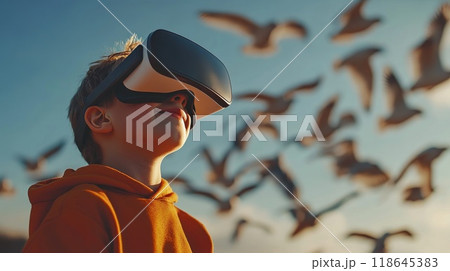 A young boy wearing a VR headset is playing a game with a flock of birds 118645383