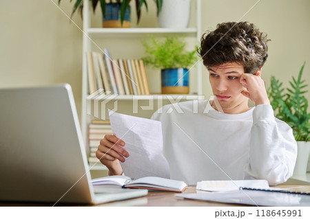 Serious young guy reading letter, paper document Serious young guy reading letter, paper document 118645991