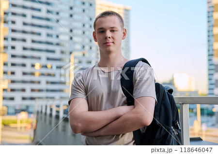 Portrait of young teenage guy looking at camera outdoors, modern skyscrapers background Portrait of young teenage guy looking at camera outdoors, modern skyscrapers background 118646047