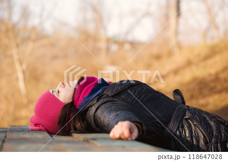 A young woman lying on a table in the garden A young woman lying on a table in the garden 118647028