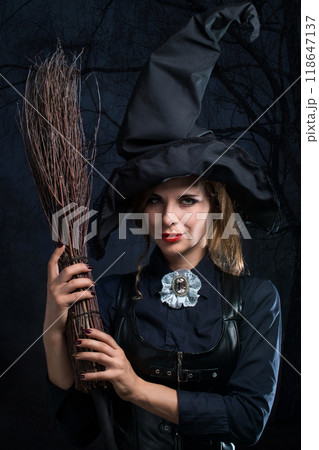 Witch in a hat and with a broom in the night spooky forest 118647137