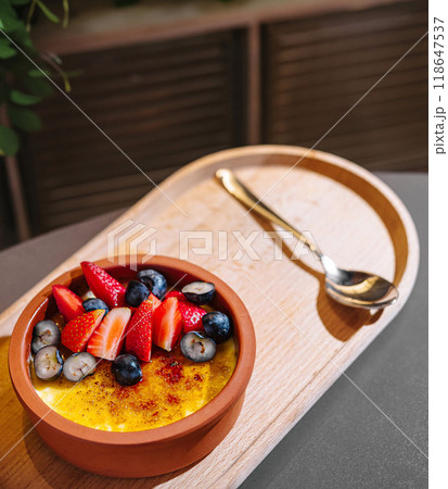 Delicious creme brulee topped with fresh berries sitting on wooden tray 118647537