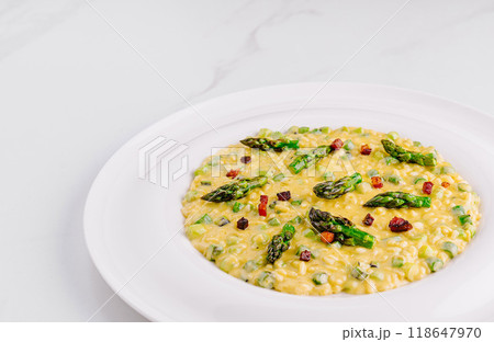 Creamy risotto with asparagus and bacon on white plate 118647970