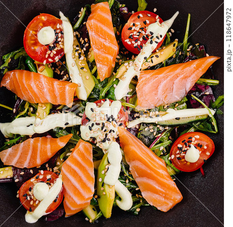 Delicious salad with salmon slices and avocado decorated with wasabi sauce and sesame seeds 118647972