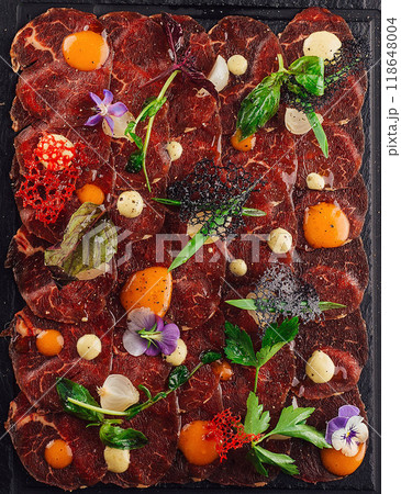 Beef carpaccio with herbs and sauces served on stone plate Beef carpaccio with herbs and sauces served on stone plate 118648004