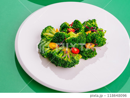 Steamed broccoli florets with tomatoes and microgreens on white plate 118648096