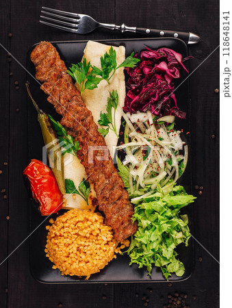 Turkish adana kebab serving on plate with vegetables, bulgur and lavash bread Turkish adana kebab serving on plate with vegetables, bulgur and lavash bread 118648141