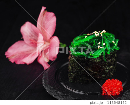 Gunkan maki sushi with green seaweed and sesame seeds on black background Gunkan maki sushi with green seaweed and sesame seeds on black background 118648152