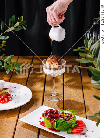 Hand pouring sauce over ice cream at gourmet dessert table 118648349