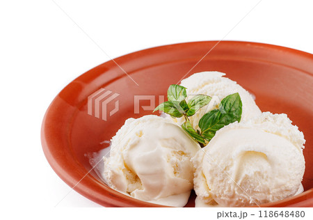 Three scoops of vanilla ice cream melting in rustic bowl with mint garnish Three scoops of vanilla ice cream melting in rustic bowl with mint garnish 118648480