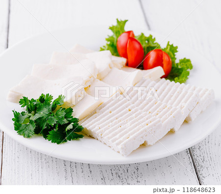 White cheese slices with cherry tomatoes and parsley on white plate 118648623