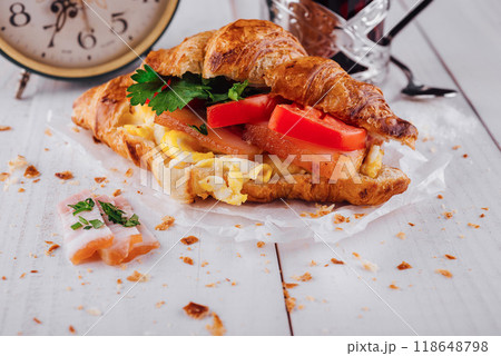 Delicious croissant filled with ham, scrambled eggs and tomato for breakfast 118648798