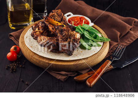 Grilled lamb ribs served on tortilla with spinach and sauce on wooden board Grilled lamb ribs served on tortilla with spinach and sauce on wooden board 118648906