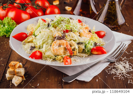 Caesar salad with shrimps being served on a white plate 118649104