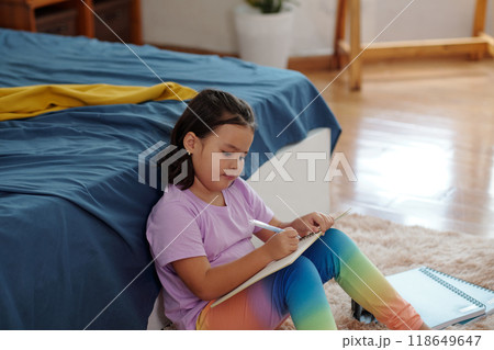 Girl Drawing Picture In Her Notebook 118649647