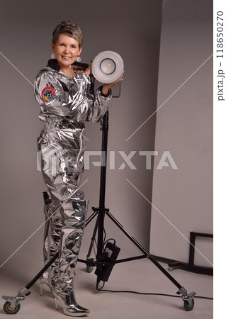 A businesswoman poses in a photo studio in a silver jumpsuit and a black stiletto dress. A businesswoman poses in a photo studio in a silver jumpsuit and a black stiletto dress. 118650270