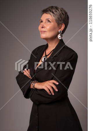 A businesswoman poses in a photo studio in a silver jumpsuit and a black stiletto dress. A businesswoman poses in a photo studio in a silver jumpsuit and a black stiletto dress. 118650276