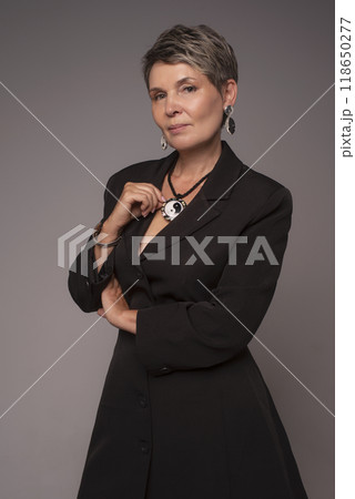 A businesswoman poses in a photo studio in a silver jumpsuit and a black stiletto dress. A businesswoman poses in a photo studio in a silver jumpsuit and a black stiletto dress. 118650277