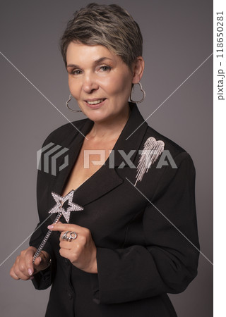 A businesswoman poses in a photo studio in a silver jumpsuit and a black stiletto dress. A businesswoman poses in a photo studio in a silver jumpsuit and a black stiletto dress. 118650281