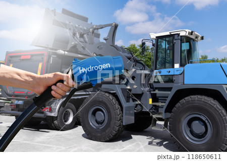Hand with hydrogen fueling nozzle on a background of fuel cell construction machines. Concept. 118650611