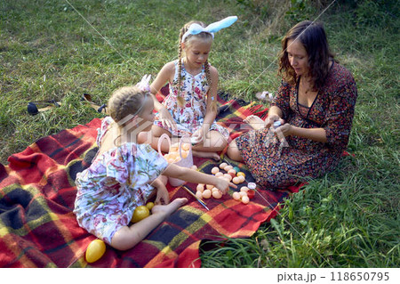 two little girls and mom paint eggs at easter picnic 118650795