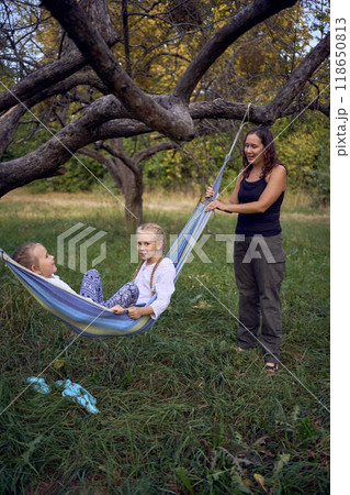 mother with little daughters playing together in  hammock, camping with children 118650813