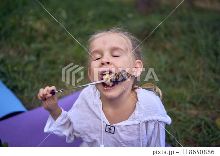 mother and her daughters roasting and eating marshmallows on the campfire, camping vacation with children, mosquito bites on children's faces mother and her daughters roasting and eating marshmallows on the campfire, camping vacation with children, mosquito bites on children's faces 118650886