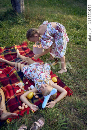 little girls, sisters, playing on a picnic blanket with eggs after an Easter egg hunt little girls, sisters, playing on a picnic blanket with eggs after an Easter egg hunt 118651046