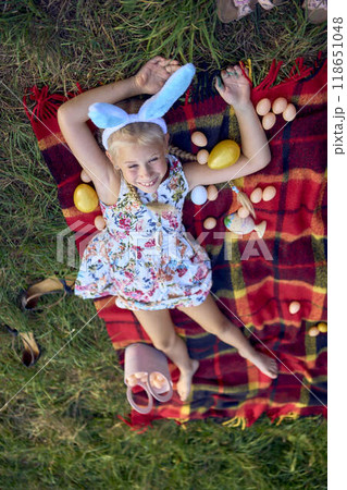 little blond girl with braids in a floral dress with a basket on an Easter egg hunt little blond girl with braids in a floral dress with a basket on an Easter egg hunt 118651048
