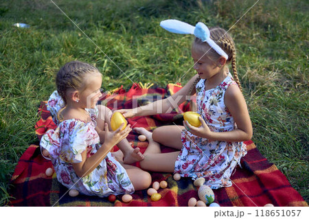 little girls, sisters, playing on a picnic blanket with eggs after an Easter egg hunt 118651057