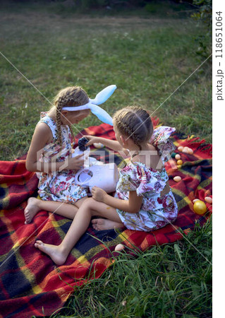 little girls, sisters, playing on a picnic blanket with eggs after an Easter egg hunt 118651064