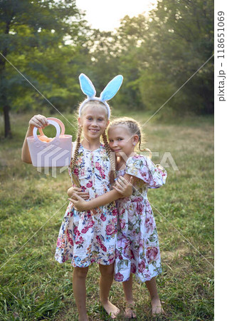 two little girls hug and play bunnies on Easter egg hunt two little girls hug and play bunnies on Easter egg hunt 118651069