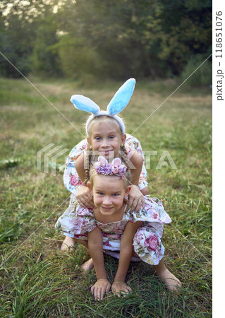 two little girls hug and play bunnies on Easter egg hunt two little girls hug and play bunnies on Easter egg hunt 118651076
