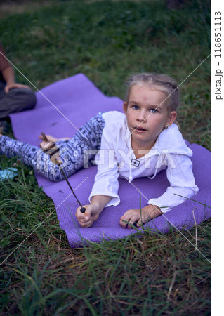 mother and her daughters  roasting and eating marshmallows on  campfire, camping vacation with children, mosquito bites on children's faces 118651113