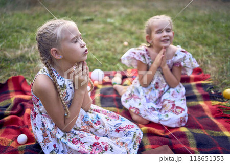 little girls sisters pray to god at easter picnic in garden little girls sisters pray to god at easter picnic in garden 118651353