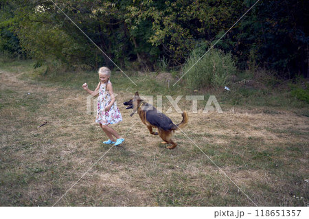 little girls sisters play with german shepherd dog during easter picnic in the garden little girls sisters play with german shepherd dog during easter picnic in the garden 118651357