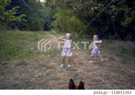 little girls sisters play with german shepherd dog during easter picnic in the garden little girls sisters play with german shepherd dog during easter picnic in the garden 118651362