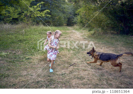 little girls sisters play with german shepherd dog during easter picnic in the garden 118651364