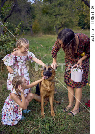 mom and little girls sisters playing with german shepherd dog during easter picnic in the garden 118651386