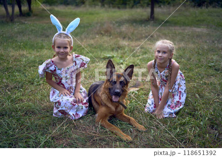 little girls sisters play with german shepherd dog during easter picnic in the garden little girls sisters play with german shepherd dog during easter picnic in the garden 118651392