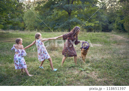 mom and little girls sisters playing with german shepherd dog during easter picnic in the garden 118651397