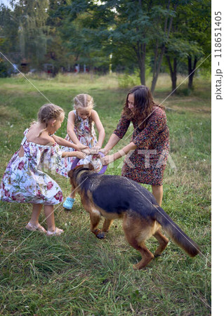 mom and little girls sisters playing with german shepherd dog during easter picnic in the garden 118651405