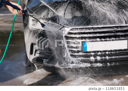 Car washing. Cleaning car using high pressure water. Middle selection of man washing his luxury car outdoor. Close-up Car washing. Cleaning car using high pressure water. Middle selection of man washing his luxury car outdoor. Close-up 118651851