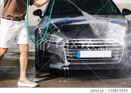 Car washing. Cleaning car using high pressure water. Middle selection of man washing his luxury car outdoor. Close-up Car washing. Cleaning car using high pressure water. Middle selection of man washing his luxury car outdoor. Close-up 118651854