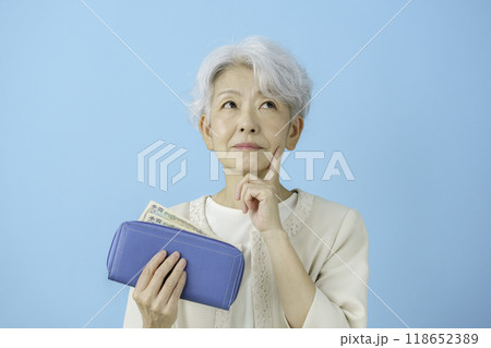 財布の中のお金を見て考え込むシニア女性 財布の中のお金を見て考え込むシニア女性 118652389