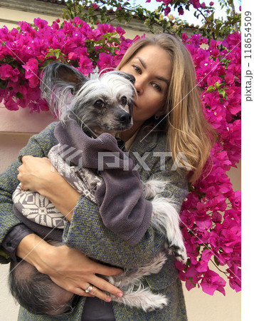 young woman with a dog in her arms on a background of flowers. Beautiful girl with a dog on a background of pink flowers 118654509