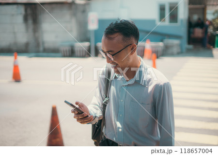 A man walks down the street, looking at his cell phone 118657004