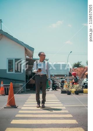 A man walks confidently through a busy crosswalk, checking his phone 118657005