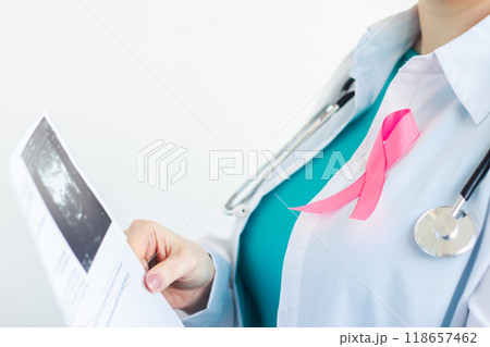 Breast cancer awareness month symbol. Woman doctor with pink ribbon on white medical uniform gives patient results of ultrasound scan. Health care concept. 118657462